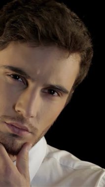 Gıcır gıcır beyaz gömlekli ve parlak siyah kravatlı yakışıklı genç bir adamın çarpıcı portresi dramatik bir siyah arka plana karşı derin bir tefekkür içinde tıraşsız çenesini okşuyor. Onun yoğun bakışları ve şık kıyafetleri güven ve güven saçıyor.