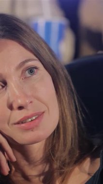 Büyüleyici orta yaşlı bir kadın çenesini elinde tutuyor, etkileyici mavi gözleri ekranda yansıyan dramayı yansıtıyor, loş, loş bir sinemada. Yumuşak gülüşü ve nişanlı tavırları sinemanın neşe ve entrikalarını çağrıştırıyor.