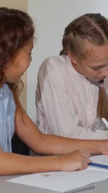 İki hevesli okul arkadaşı, canlı kızıl saçlı bir kız ve neşeli sarışın arkadaşı canlı bir sanat sınıfında renkli çizimlerini tartışıyorlar. Bu iç açıcı sahne güzel bir şekilde ruhun özetini içeriyor.