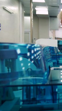 Son teknoloji ürünü bir laboratuarda, beyaz labaratuvar önlüklü seçkin gri saçlı bir adam mavi renkli gelişmiş laboratuvar ekipmanlarını titizlikle inceliyor. Elindeki yoğun bakışları ve not panosu hassasiyete derin bir bağlılığı yansıtıyor.