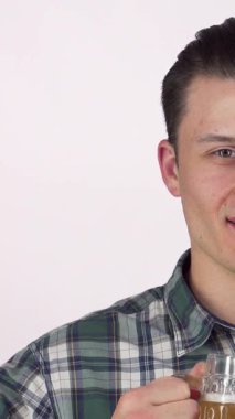 Neşeli bir sırıtışla keyifli bir genç adam soğuk bir bardak biradan bir yudum alır ve kutlamanın özünü yakalar. Şık ekose gömleği bu anı canlı toplantılar ve hafta sonu şenlikleri için ideal kılıyor.