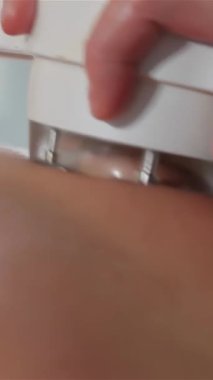 Yetenekli bir kadın masör, bir kadının belinden ustalıkla bir masaj makinesinin başını süzüp rahatlamanın ve gençleşmenin huzurlu atmosferini yaratır. Yakın çekim, tendeki yumuşak baskıyı ortaya çıkararak rahatlatıcı atmosferi vurguluyor.