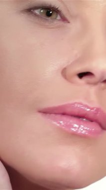 Güzel beyaz bir kadının büyüleyici yakın çekimi kusursuz tenine nazikçe dokunuyor, yumuşak beyaz bir zemine kuruluyor. Parlak teni ve çarpıcı yeşil gözleri zarafet ve güven saçıyor, hayranlık ve ilham uyandırıyor.