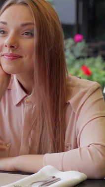 İki güzel kadın, birinin uzun dalgalı saçları, diğerinin parlak bir gülümsemesi var, büyüleyici bir kafe terasında oturuyorlar, canlı kokteylleri yudumlarken birbirlerine sırlarını anlatıyorlar. Yeşillik ve rengarenk çiçekler etraflarını sarar.