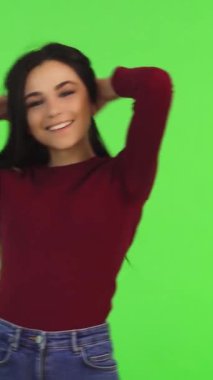 Uzun, dalgalı saçları olan enerjik genç bir kadın hayat dolu yeşil bir zemine ışıldarken buklelerini şaklatarak çeviriyor. Onun kaygısız duruşu ve ışıl ışıl gülüşü gençlik güzelliğinin ve coşkunluğunun özünü somutlaştıran kendine güven ve canlılık saçıyor.