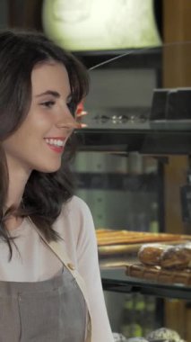 Neşeli genç bir fırıncı, baştan çıkarıcı yeni pişmiş hamur işleri ve zanaatkar ekmeklerle çevrili kameraya sıcak bir şekilde gülümsüyor. Sevgiyle sunarken coşkulu ruhu ışıldıyor. Lezzetli eserleri müşterileri eğlenmeye davet ediyor.