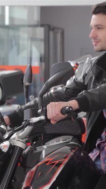 Tarz sahibi beyaz bir adam parlak siyah bir motosiklete güvenerek oturur, odaklanmış bir bakışla gidonu ustalıkla manevra yapar. Parıldayan benzin deposuna dokunduğunda heyecanı yayılıyor. Heyecan verici bir deneyim yaşıyor.