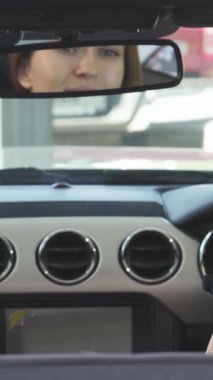 Uzun, dalgalı saçları olan neşeli genç bir kadın omuzlarının üzerinden, macera ve özgürlüğün ruhunu somutlaştıran şık, üstü açık arabasından bakarken neşe saçıyor. Bu canlı sahne, açık yolda gezinmenin coşkulu hissini yakalıyor.