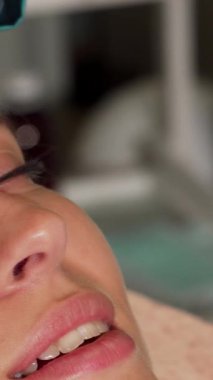 Huzurlu genç bir kadın ultrasonik bir yüz tedavisiyle rahatlamanın tadını çıkarıyor. Gözleri yavaşça saf mutlulukla kapanıyor. Uzman güzellik uzmanı cildini derin bir şekilde arındırmak ve tazelemek için ultrasonik aletler kullanıyor.