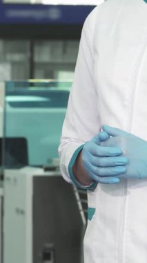 Üst düzey bir tıp laboratuarında, beyaz önlüklü ve mavi eldivenli odaklanmış bir kadın biyolog asistanından canlı bir kan testi tüpü alır. Bu dinamik değişim, hayati takım çalışmasının ve hassasiyetin göstergesidir.