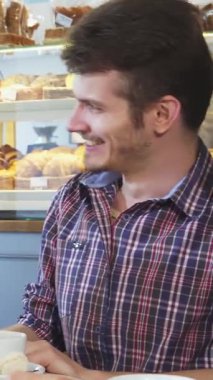 Büyüleyici bir kahve dükkanında, yakışıklı bir adam ve güzel bir kadın, lezzetli hamur işleriyle çevrili, dumanı tüten kahve fincanlarının üzerinde neşeli bir kahkaha atarlar. Enerjileri ve sıcak gülümsemeleri davetkar bir atmosfer yaratıyor.