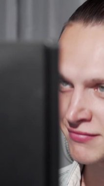 Çarpıcı mavi gözleri olan odaklanmış genç bir adam dinamik bir video çağrısına dalmış, yoğun bakışları bilgisayar ekranına sabitlenmiş. İnce ışıklandırmayla süslenmiş modern çalışma alanının gösterişli tasarımı dijital ortamın atmosferini yükseltiyor.