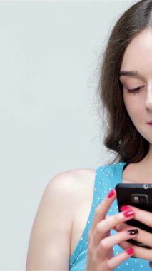 Akıllı telefonuyla uğraşırken neşe saçan dalgalı kahverengi saçlı ışıltılı genç bir kız, şakacı bir şekilde onaylıyor. Canlı mavi bir atlet giymişti. Neşeli tavırları ve şık görünüşü davetkar bir pozitiflik atmosferi yaratıyordu.