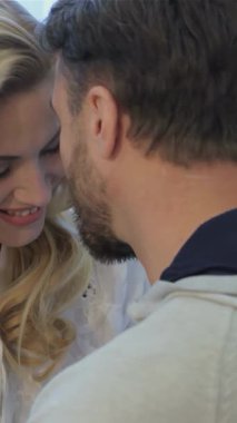 Çekici esmer bir adam ve onun çarpıcı sarışın karısı evde hassas bir anı paylaşıyorlar, alınları tatlı bir kucaklaşmayla nazikçe birbirine dokunuyor. Saf perdelerin arasından süzülen yumuşak, altın ışık güzel ve davetkar bir atmosfer yaratır.