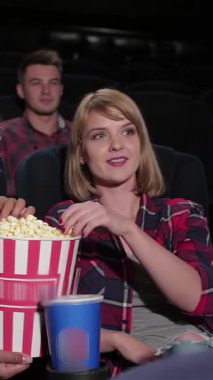 Canlı bir grup genç arkadaş ellerinde patlamış mısır kovaları ve ellerinde içkilerle rahat bir multiplex tiyatrosunda film gecesinin heyecanıyla eğleniyorlar. Animasyon ifadeleri ve kahkahaları bir elektrik atmosferi yaratıyor,