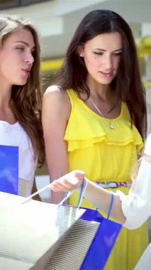 Her biri renkli alışveriş torbalarını tutan üç modaya uygun genç kadın şık bir alışveriş merkezinin dışında bulaşıcı bir kahkaha paylaşıyorlar. Şık kıyafetleri ve ışıl ışıl gülümsemeleri arkadaşlığın ve perakende terapinin özünü yansıtıyor.