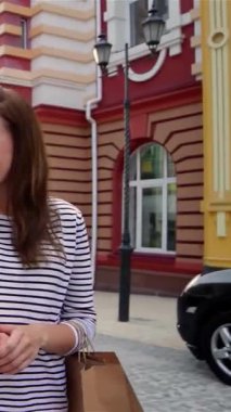 Saf neşe saçan iki neşeli kız, her biri şık alışveriş torbalarına sarılmış, keyifli bir şehir caddesinde geziniyorlar. Bulaşıcı gülüşleri ve ışıl ışıl gülüşleri renkli binaların büyüleyici zeminini aydınlatıyor.