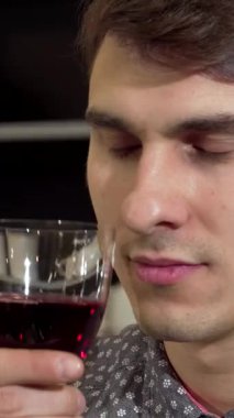 Kibar bir gülümsemesi olan çekici bir genç adam şık dairesinde nefis kırmızı şarap kokusunun tadını çıkarıyor. Rahat tavrı ve düşünceli bakışı uzun bir süre sonra gevşemek için mükemmel bir eğlence ve sofistike atmosfer yaratıyor.