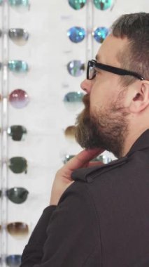 Sakallı olgun bir adam, gözlükçülerin dükkanında göz kamaştırıcı bir güneş gözlüğü dizisini keşfederken omzunun üzerinden ışıldıyor. Neşeli tavırları heyecan saçıyor. Alışverişini yükselten renk ve stillerden oluşan bir kaleydoskopla çevrili.