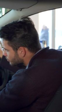 Şık, esmer, bakımlı sakallı bir adam neşeli bir galeride lüks ve modern bir arabada otururken başparmağını kaldırıyor. Bulaşıcı gülüşü ve lüks iç görünüşü heyecan dolu bir atmosfer yaratıyor, mükemmel bir şekilde yakalıyor.