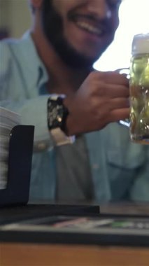 Yüzleri neşeyle parlayan, hareketli bir barda buzlu bira bardaklarını kaldıran, takımlarında zaferle eğlenen üç coşkulu adam. Neşeli atmosfer kahkaha ve dostlukla uğulduyor. Dostlar başarının şerefine kadeh kaldırıyor.