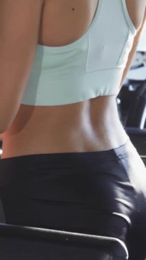 Büyüleyici bir görüntü, şık bir spor sutyen ve parlak siyah taytlar giyen, koşu bandında güvenle yürüyen zinde bir genç kadını gösteriyor. Onun ışıl ışıl gülüşü ve tonlu fiziği motivasyon ve pozitiflik yayar, diğerlerini canlı ve canlı bir şekilde kucaklamaya davet eder.