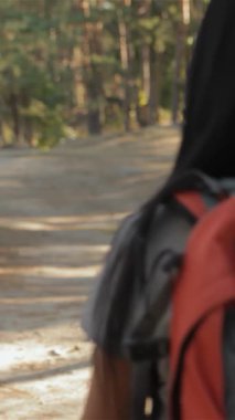 Neşeli bir çift, yemyeşil ve yüksek ağaçlarla çevrili güneşli orman patikası boyunca el ele yürür. Parlak turuncu bir sırt çantası olan çekici esmer kadın, sakallı erkek arkadaşıyla ışıl ışıl bir gülümseme paylaşıyor.