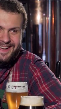 Ekose gömlekli ve önlüklü neşeli bir barmen gülümseyen bir müşteriyle neşeyle kadeh tokuşturur, sıcaklık ve dostluk saçar. Parıldayan musluklar ve köpüklü bira ile vurgulanan atmosferi davet eden çubuklar, hayat dolu bir ortam hazırlıyor.