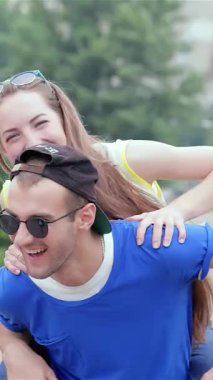 Işıl ışıl bir çift açık havada güneşli bir günün keyfini çıkarırken, adam neşeli bir şekilde arkadaşlarının fotoğraflarını çekiyor. Bulaşıcı kahkahaları ve enerjik enerjileri dostluk ve neşe dolu canlı bir atmosfer yaratıyor.