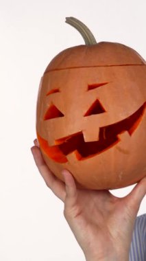 Neşeli, kırmızı dudaklı genç bir kadın tuhaf bir şekilde oyulmuş Cadılar Bayramı balkabağıyla eğlenceli bir şekilde selfie çeker. Heyecan saçar. Sahne sonbahar cazibesiyle patlar, onun neşeli kişiliğini ve büyüleyici ruhunu yakalar.