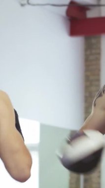 Adanmış üstsüz bir MMA koçu, enerjik bir spor salonunda yüksek enerjili bir antrenman sırasında genç bir erkek dövüşçüye tutkuyla talimat veriyor. Güçlü yumruklar ve savunma manevraları birbirlerine bağlılıklarını gösterirken hava şiddetle çatırdıyor.