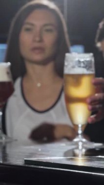 Ön planda çıtır çıtır, altın bir bira parlarken genç bir çift, bir erkek ve bir kadın coşkulu bir barda kutlama yapmak için kadehlerini tokuşturuyorlar. Bu canlı sahne, sevgi ve dostluğun özünü yansıtan sıcaklığı ve bağlantıyı yansıtıyor.