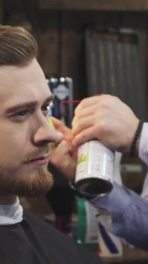 Yakışıklı, sakallı bir adamın büyüleyici yakın çekimi, yetenekli bir berber gibi sırıtarak ateşli bir saç tedavisiyle havada heyecan yaratır. Titrek alevler şık berber dükkanını aydınlatıyor, sanatını ve hassasiyetini sergiliyor.