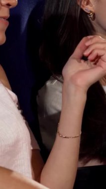 Canlı bir sinema ortamında, iki neşeli bayan arkadaş komedi filmi izlerken tereyağlı patlamış mısırın tadını çıkarırken bir anlık neşe paylaşıyorlar. Bulaşıcı gülüşleri ve ışıl ışıl gülümsemeleri dostluk ve heyecan dolu bir atmosfer yaratıyor.