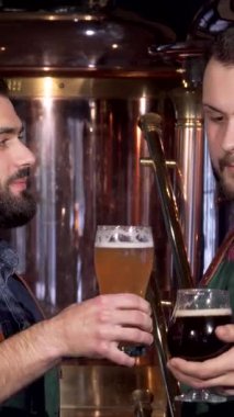 İki tutkulu bira imalatçısı, biri şık sakallı ve diğeri canlı ekose gömlekli, neşeyle bardaklarını altın ve siyah zanaat biralarıyla dolduruyorlar. Parlayan bakır tanklar ve zengin ahşaplarla vurgulanmış bira fabrikasının sıcak parıltısı.