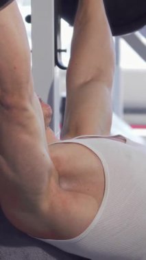 Odaklanmış kaslı bir adam, şık ve modern bir spor salonunda ağırlık kaldırırken ağır bir halteri kaldırır. Keskin fiziği ve sarsılmaz kararlılığı güç ve adanmışlık saçıyor. Formda olmanın ve atletik maharetin özünü yakalıyor.