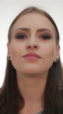 Sevimli genç bir kadın şakacı bir şekilde kameraya bir öpücük yolluyor büyüleyici gülümsemesi sıcaklığı ve kendine güveni yayıyor. El değmemiş beyaz bir zemin üzerine kurulmuş çarpıcı özellikleri ve etkileyici gözleri canlı ve davetkar bir atmosfer yaratıyor.