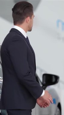 Genç bir adamla profesyonel bir araba satıcısı arasında coşkulu bir tokalaşma şık, modern bir galeride yeni bir araba satın alma heyecanını yayar. Işıldayan araç ve çağdaş tasarım otomotiv yeniliğinin heyecanını arttırıyor ve