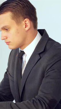 Özel dikim takım elbiseli genç bir erkek işadamı, parlak dizüstü bilgisayarındaki verileri yoğun bir şekilde analiz ederek profesyonellik ve hırs yayıyor. Minimalist ofis arkaplanı, hafif ışıklandırmayla, konsantrasyon ve stratejik karar atmosferini güçlendirir.