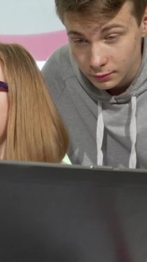 Renkli bir okul kütüphanesine dalmış iki kız ve iki oğlandan oluşan dinamik bir grup, bir dizüstü bilgisayarın etrafında hevesle iş birliği yapıyor, yüzleri heyecan ve merakla parlıyor. Bu canlı sahne takım çalışmasının ve akademik gelişimin özünü yansıtıyor.