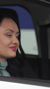 Işıl ışıl gülümseyen kendine güvenen genç bir kadın arabasının anahtarını yüksek tutuyor, lüks ve modern bir bayilikte heyecan saçıyor. Parlak araçlar ve çağdaş dekorlarla süslenmiş canlı sergi salonu, yeni heyecanı sembolize ederek neşesini artırıyor.