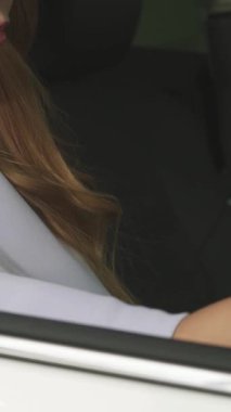 Canlı bir yakın plan fotoğraf, uzun, dalgalı saçlı neşeli bir kadın modern aracında otururken kendine güveni tam bir araba anahtarı tutuyor. Bu görüntü pozitif ve heyecan saçıyor, araba sahibi olmanın heyecanını ve yeni bir hayatın neşesini yakalıyor.