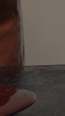 Canlı bir mutfakta, parlak bir önlük ve eldiven giymiş kendini adamış bir çikolatacı, parlak bir tezgahın üzerinde ustalıkla, pürüzsüz, lezzetli bir çikolata yiyor. Bu dinamik sahne, gurme yaratmanın arkasındaki titiz sanat ve tutkuyu gözler önüne seriyor.