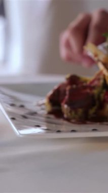 Yakından çekilen bir fotoğraf, bir çatalın, canlı otlar ve zengin soslarla süslenmiş taze eti ortaya çıkararak, incelikle kaplanmış bir gurme tabağını kestiği anı yakalar. Bu nefis sahne, güzel bir akşam yemeğinin zarafetini temsil ediyor.