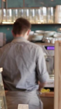 Çekici bir kafede, sıcak kalpli bir barista neşeli genç bir kıza gözleri heyecandan parlayan dumanı tüten bir latte sunar. Davetkar ortam, taze demlenmiş kahvenin zengin aromasıyla zenginleşir.