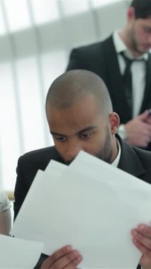 Kendine güvenen dört işadamı ve işkadınından oluşan odaklanmış bir grup, parlak, güneşli bir ofis masasında dinamik bir tartışmaya dalmış, belgeleri analiz ediyor ve yenilikçi stratejiler paylaşıyorlar. Enerjik etkileşimleri hırs yayıyor.