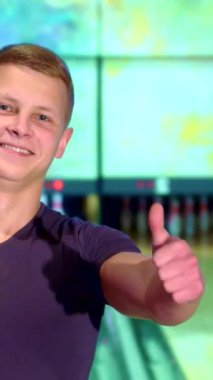 Neşeli, genç, beyaz bir adam, renkli ışıklar ve parlak şeritlerle dolu, canlı bir bowling salonunda heyecan saçıyor. Enerjik atmosfer ve canlı renkler bu heyecan verici bowling macerası için mükemmel bir zemin oluşturuyor.