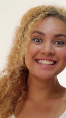 İki genç kadın neşeli bir anı paylaşıyor, bir fısıldayan sırla diğerlerinin kulağına, ılık ve samimiyet saçan yumuşak beyaz bir zemin. Kahverengi saçlı beyaz kızların gözlerindeki heyecan kızıl saçlı arkadaşının öne eğilmesiyle ışıldıyor.