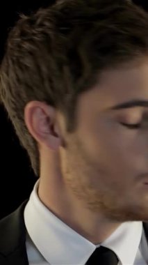 Siyah takım elbiseli kararlı genç bir adam dürbünle ufku yoğun bir şekilde tarıyor ve bir amaç ve aciliyet duygusunu somutlaştırıyor. Giyim tarzının ince çizgileri koyu arka planla keskin bir şekilde tezat oluşturuyor, gizem ve entrika havasını arttırıyor.