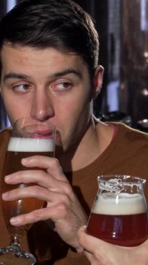 Çekici bir adam ve kız arkadaşı neşeli bir kahkahayı canlı bir barda el sanatları biralarını tokuştururken, özel bir gecede aşklarını kutlarken paylaşıyorlar. Sıcak, davetkar atmosfer kahkaha sesleri ve bardakların tıkırtısıyla doluydu.